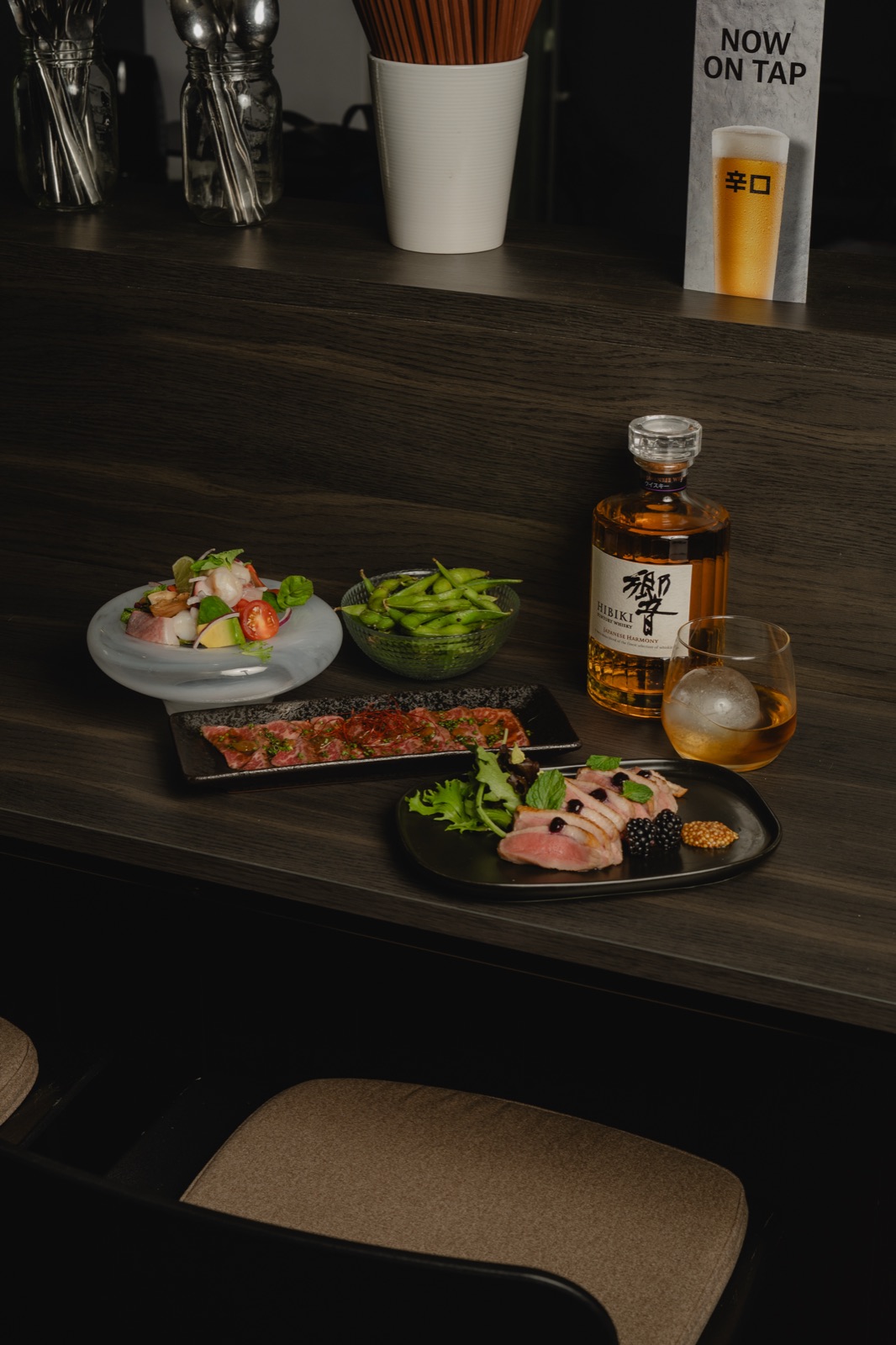 Salad, edamame, wagyu tataki and duck slices beside a bottle of Hibiki whisky