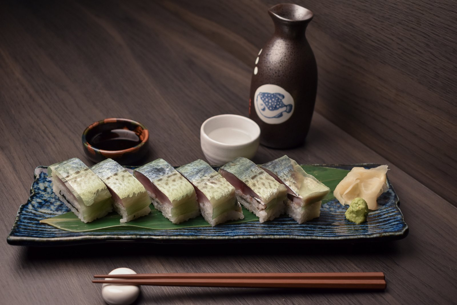 Battera oshizushi beside a sake bottle and cup