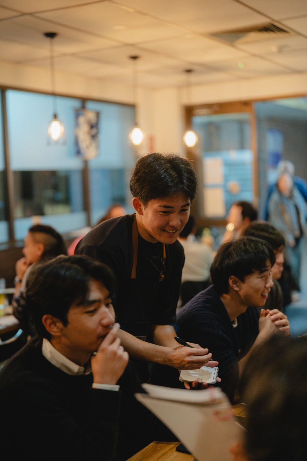 A Sake Zen server chatting with guests at their table