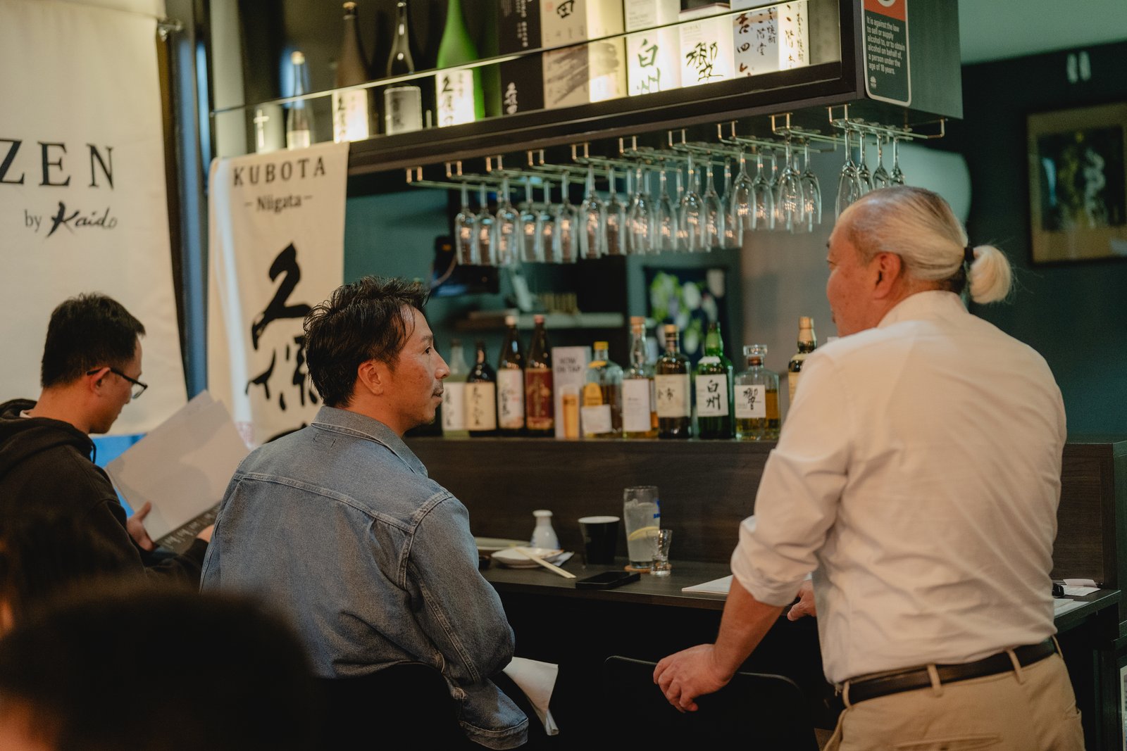 A Sake Zen bartender attending to a guest at the bar