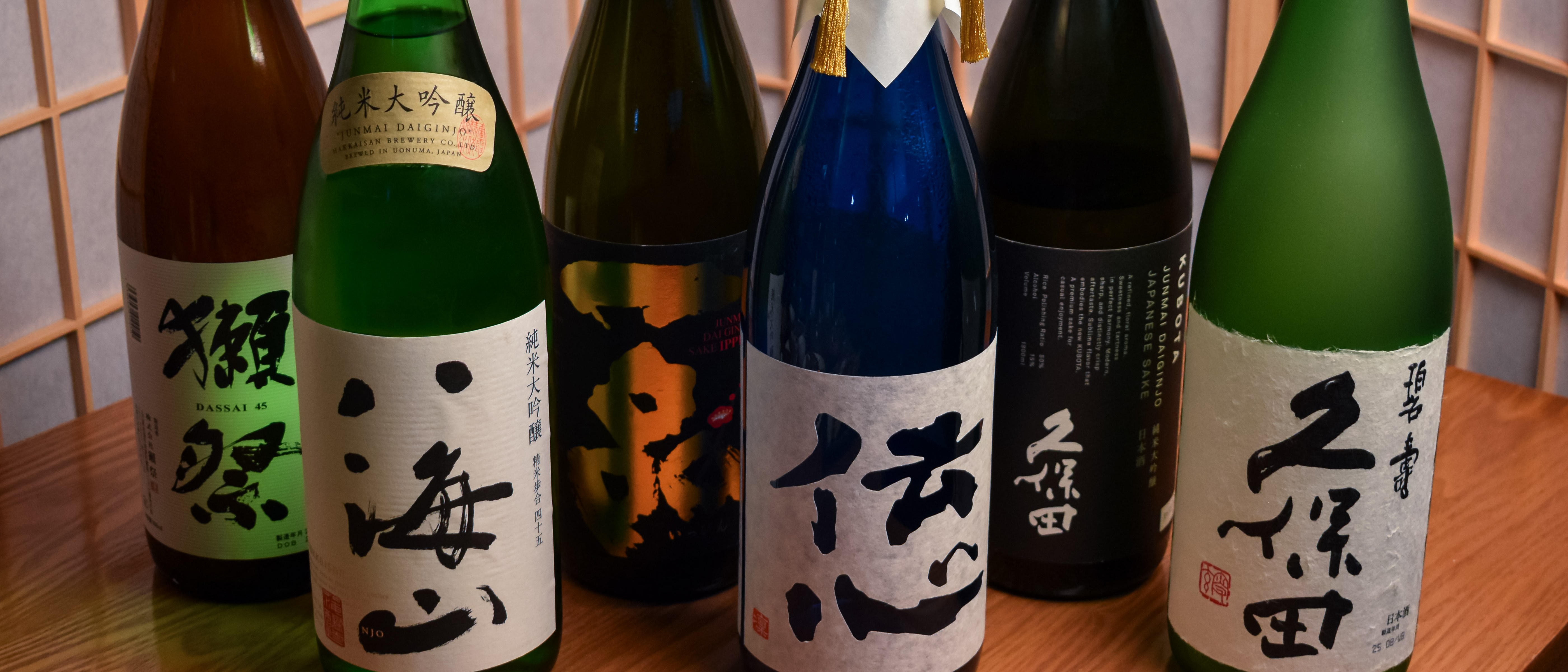Sake bottles lined up on a softly lit shelf at Sake Zen